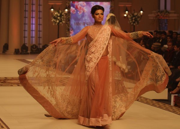 पाकिस्तान के लाहौर में शुक्रवार 12 दिसंबर को आयोजित The Telenor Bridal Couture Week 2014 के दौरान पाक डिज़ाइनर आमर शाहिद की डिजाइन को पेश करती पाकिस्तानी मॉडल। (फ़ोटो-एपी)