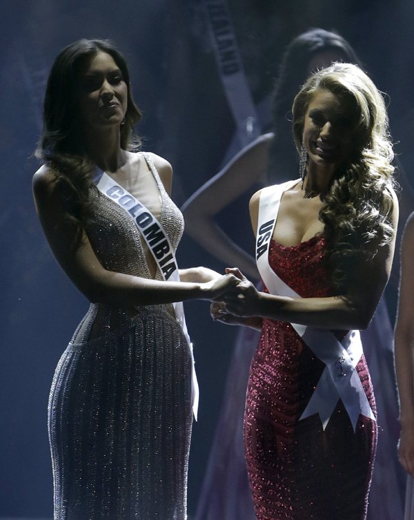 Miss Universe: मिस यूनिवर्स पाउलीन वेगा (दाएं) और मिस यूएसए निया सेंचेज़ स्टेज पर एक-दूसरे का हाथ थामकर 63वें मिस यूनिवर्स सौंदर्य प्रतियोगिता के विजेता के नाम का इंतज़ार करते हुए। (स्रोत-एपी)