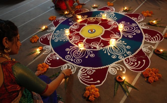 Hindu women arrange oil lamps and flowers around a "Rangoli", a traditional pattern made from coloured powders, during the celebrations ahead of the Hindu festival of Diwali in the western Indian city of Ahmedabad November 1, 2013. Diwali, the annual festival of lights will be celebrated across the country on November 3. REUTERS/Amit Dave (INDIA - Tags: RELIGION SOCIETY) - RTX14WIF
