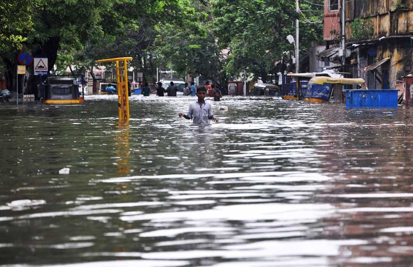 चेन्नई में बारिश से भरी सड़क को पार करता एक लड़का। (पीटीआई फोटो)