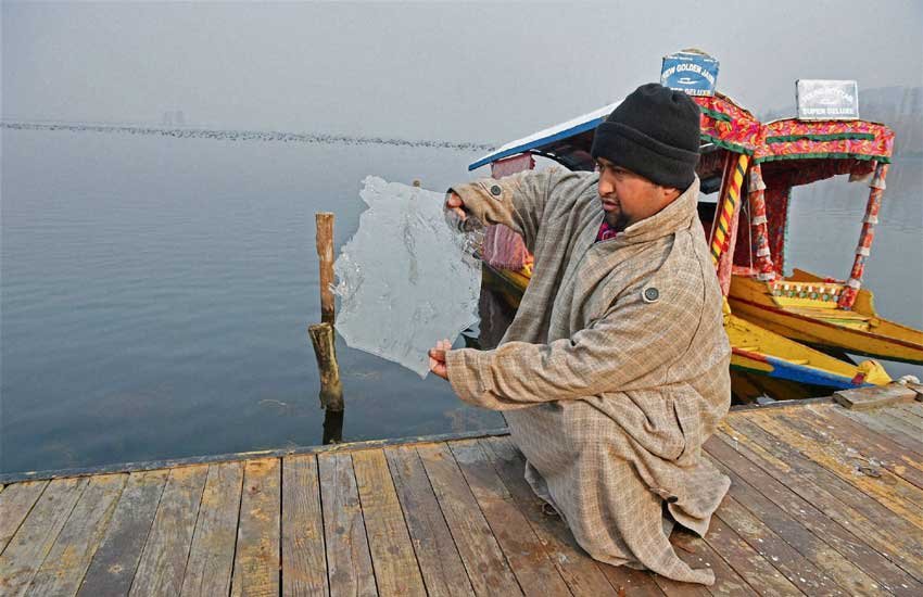 ठंड से जमी डल झील का एक टुकड़ा दिखाता नाविक। शनिवार को यहां का तापमान -4 डिग्री तक गिर गया। (पीटीआई फोटो) 