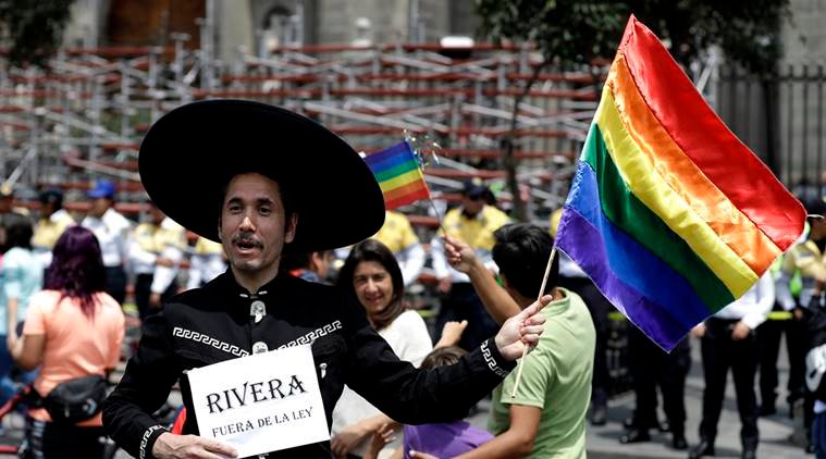 A man dressed as a Mexican cowboy and holding a rainbow flag smiles as he poses for a portrait during a gay rights demonstration outside of Mexico City's Metropolitan Cathedral in Mexico City, Sunday, Sept. 11, 2016. Hundreds of gay and lesbian rights supporters marched to Mexico City's Metropolitan Cathedral to support gay marriage. (AP Photo/Eduardo Verdugo)