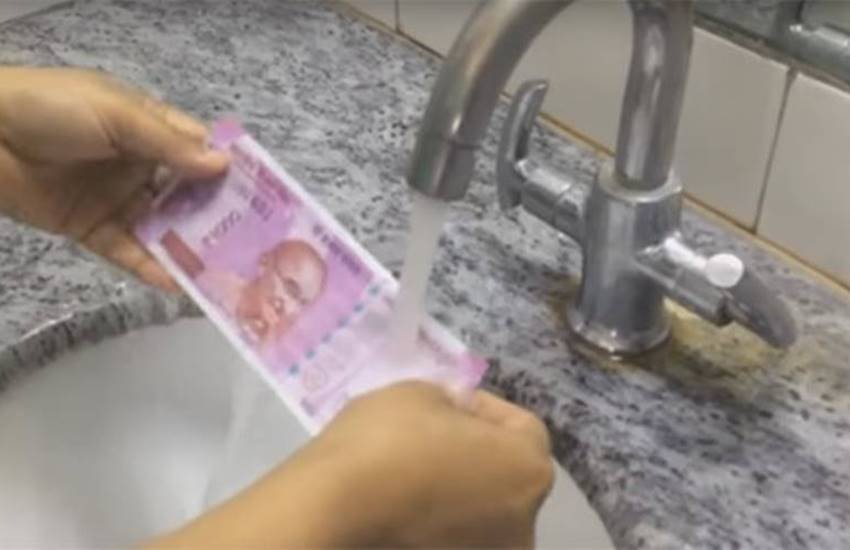 2000 रुपए का नया नोट पानी में धोता एक युवक। (Photo Source: Youtube)