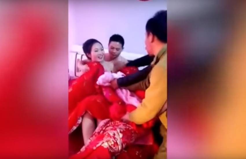 चीन में अनोखी परंपरा, शादी के बाद दुल्हे के दोस्त उतारते हैं दुल्हन के कपड़े। (Photo Source: Youtube/Miaopai)