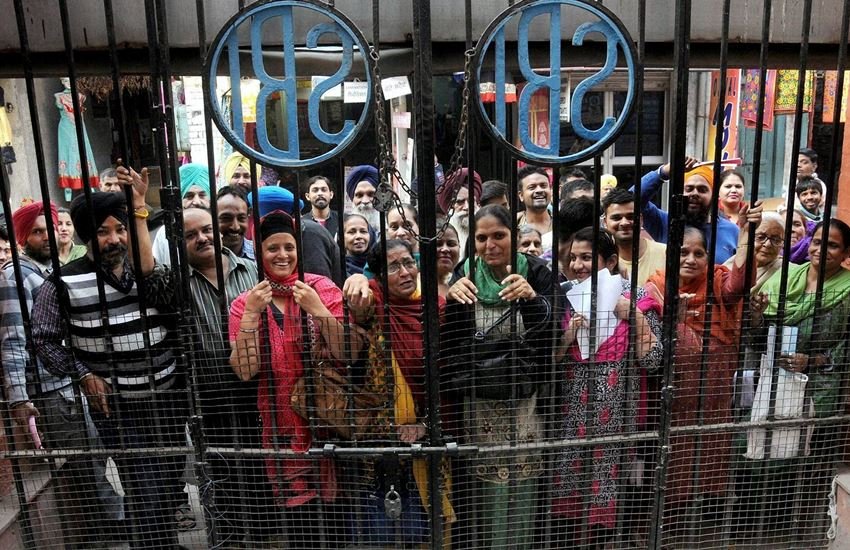 नोटबंदी से परेशान लोग बैंक के बाहर खड़े हुए।