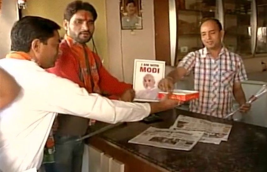 एक कारोबारी को मिठाई देते हुए बीजेपी के कार्यकर्ता। (Source: Agencies)