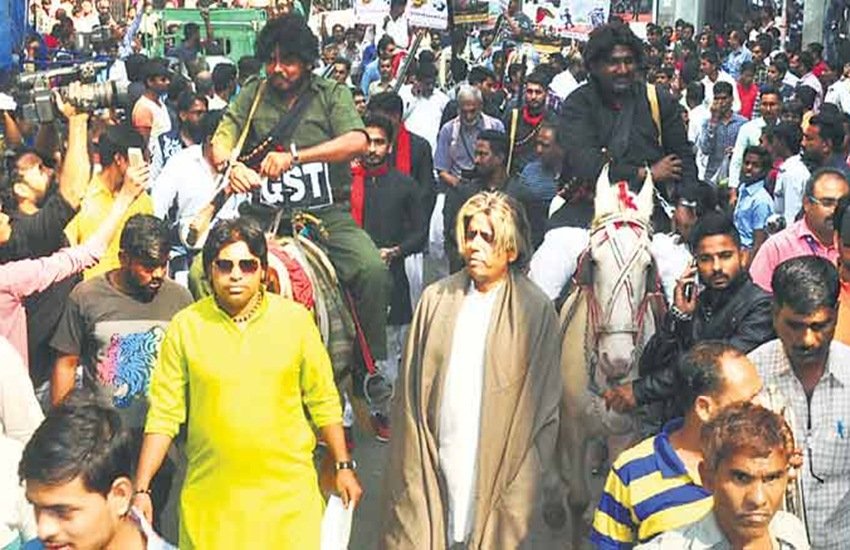 सूरत में मंगलवार को कांग्रेस ने खास तरह से विरोध प्रदर्शन किया, जिसमें घोड़े पर गब्बर सिंह को बैठाकर शहर भर में घुमाया गया। गब्बर के कॉस्ट्यूम के ऊपर जीएसटी लिखा हुआ था। (फोटोः इंडियन एक्सप्रेस)
