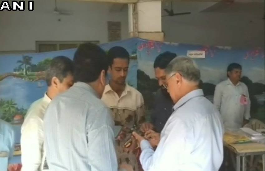 गुजरात चुनाव के पहले चरण में पोरबंदर के एक बूथ पर ईवीएम की ब्लूटूथ से कनेक्टिविटी की जांच करते चुनाव आयोग के अधिकारी। (फोटो- ANI)