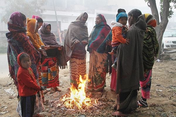 जम्मू में ठंड से बचने के लिए हाथ सेंकते कुछ महिलाएं और बच्चे। (PTI Photo)