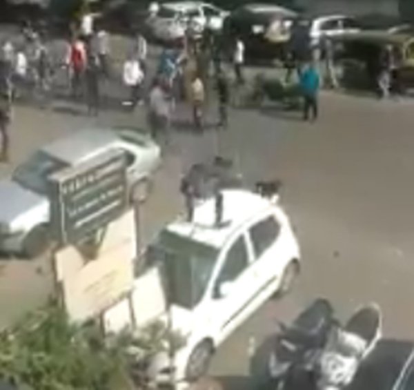 बंद के दौरान कार पर चढ़कर कार के ऊपर पत्थर मारता एक युवक।