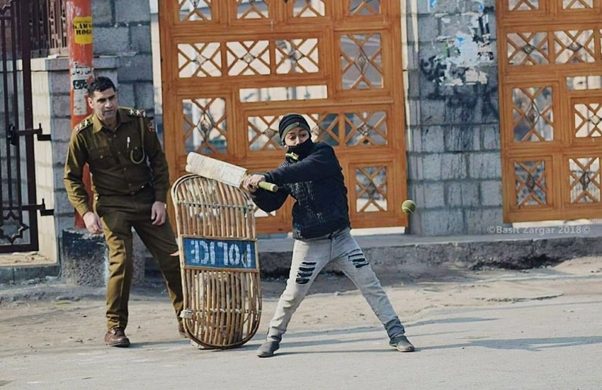 कश्मीरी बच्चे के साथ क्रिकेट खेलता पुलिसवाला। (फोटो सोर्स - BASIT ZARGAR‏ Twitter)
