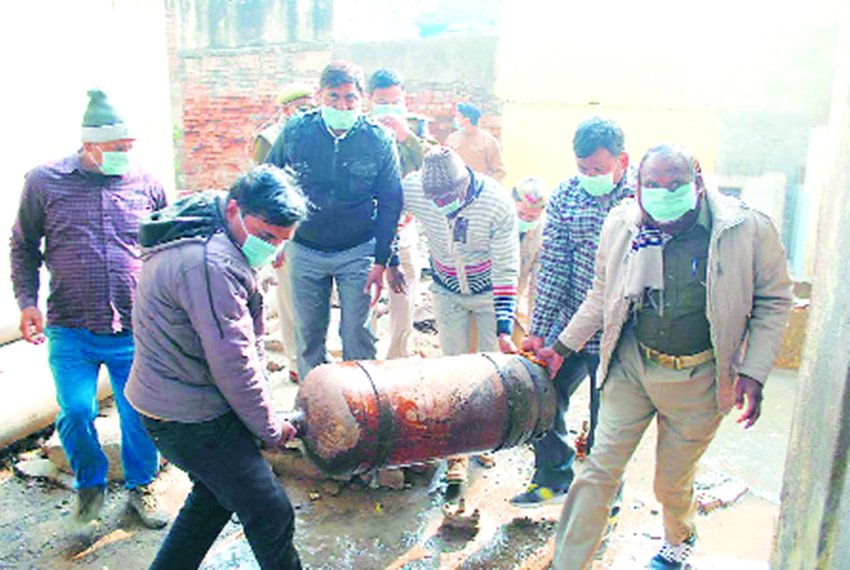 दमकल विभाग के कर्मचारी सिलेंडर को बाहर ले जाते हुए