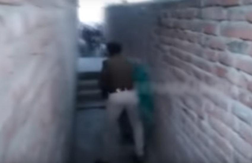 महिला को पीटता पुलिसकर्मी।