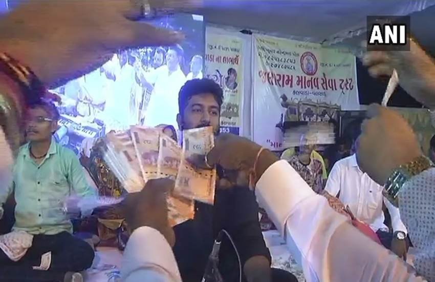 गुजरात में वलसाड जिले में कार्यक्रम के दौरान लोकगायक पर नोटों की बारिश्ा करते लोग। फोटो- एएनअाई गुजरात में वलसाड जिले में कार्यक्रम के दौरान लोकगायक पर नोटों की बारिश्ा करते लोग। फोटो- एएनअाई