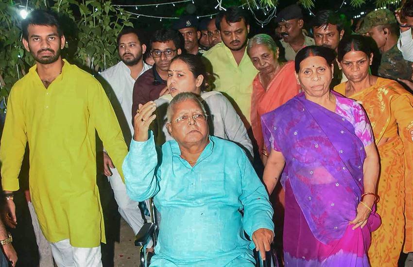 लालू के गुरुवार को पटना में पहुंचने पर उन्हें व्हीलचेयर पर लेकर जाते परिजन। (फोटोः पीटीआई)