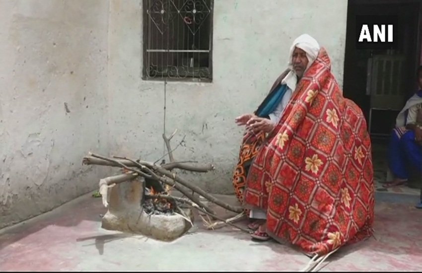 जून की भीषण गर्मी में रजाई ओढ़कर आग तापते हरियाणा के संतराम। फोटो- एएनआई