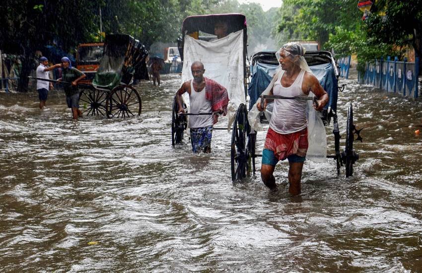 कोलकाता में बरसात के बाद पानी से भरी गली से निकलता हुआ रिक्शा चालक। फोटो- पीटीआई
