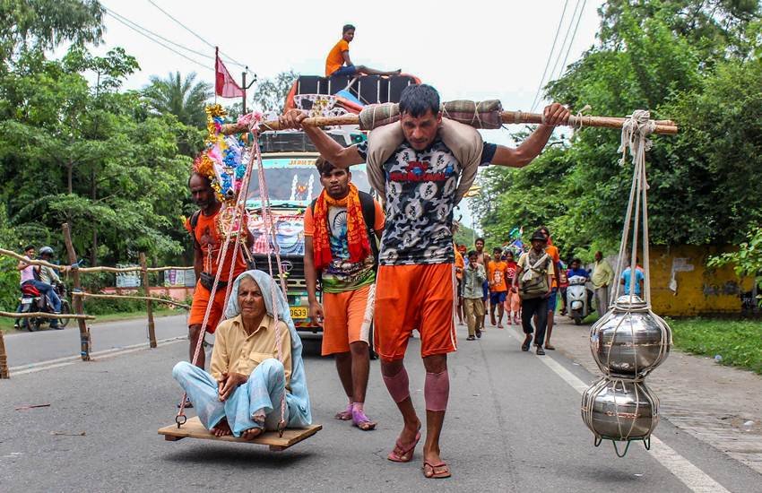 मेरठ में वृद्धा महिला के साथ कांवड़ लेकर निकलता श्रद्धालु। फोटो- पीटीआई