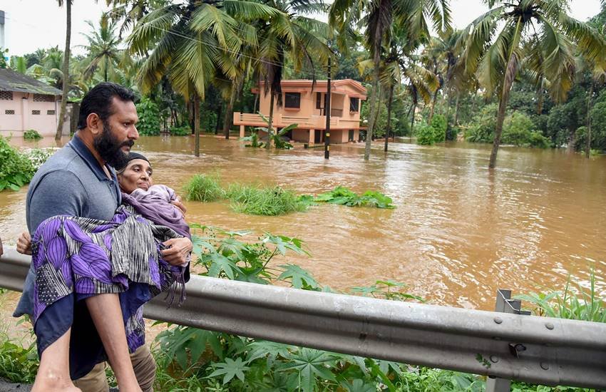 केरल में बाढ़ग्रस्‍त इलाके से महिला को निकालता राहत कर्मी। (Photo : PTI File)