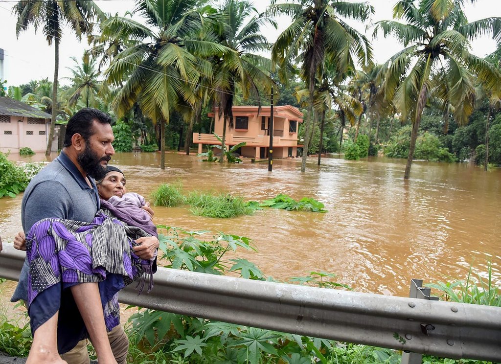 केरल में बाढ़ग्रस्‍त इलाके से महिला को निकालता राहत कर्मी। (Photo : PTI File)