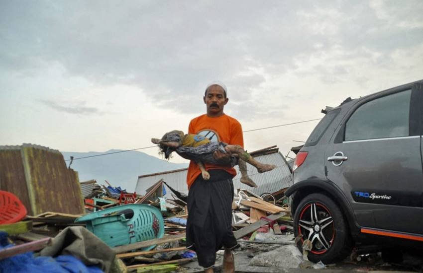 सुनामी में मारे गए बच्‍चे का शव ले जाता पिता। (Photo : AP)