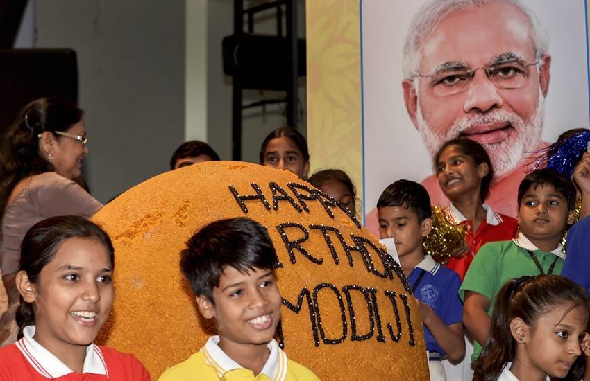 नई दिल्‍ली: प्रधानमंत्री नरेंद्र मोदी के जन्‍मदिन पर 568 किलो के लड्डू के साथ पोज देते स्‍कूली बच्‍चे। (Photo : PTI)