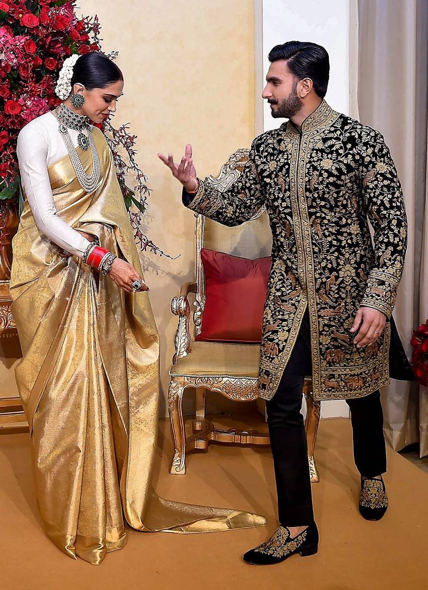 दीपिका की साड़ी संभालने के बाद रणवीर जैसे उनसे कह रहे हों- देखा मेरे हाथ का कमाल! (फोटो - पीटीआई)
