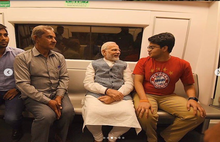दिल्ली मेट्रो में यात्रा के दौरान यात्रियों से बातचीत करते पीएम नरेंद्र मोदी।