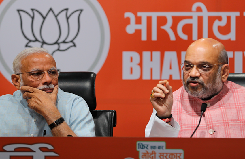 Loksabha Elections 2019: नई दिल्ली स्थित पार्टी मुख्यालय पर पत्रकारों के सवालों के जवाब देते हुए बीजेपी चीफ अमित शाह, जबकि उनकी बात ध्यान से सुनते हुए पीएम नरेंद्र मोदी। (फोटोः पीटीआई)