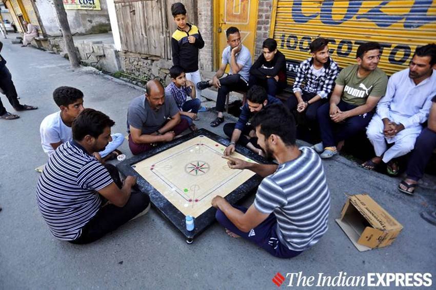 श्रीनगर में बंद दुकानों के बाहर सड़क पर कैरम खेलते घाटी के युवा।