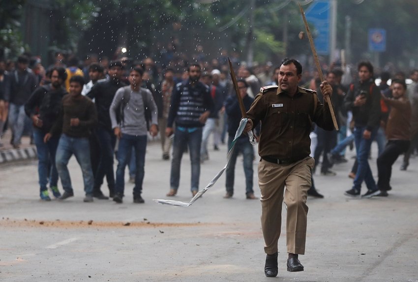जामिया में भी नागरिकता कानून के खिलाफ प्रदर्शन पर बैठे छात्रों में पुलिसवालों पर पत्थरबाजी की। तस्वीर में एक पुलिसवाला उग्र प्रदर्शनकारियों से बचने के लिए भागता हुआ दिख रहा है। (Photo: REUTERS/Adnan Abidi)