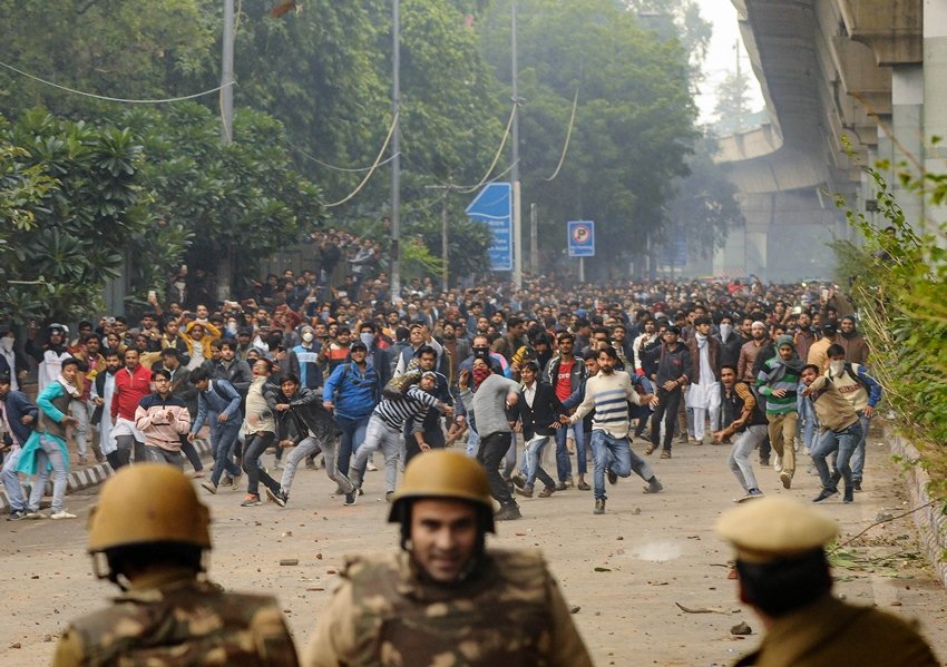 जामिया के प्रदर्शनकारी छात्र पुलिस बल पर पत्थर फेंकते हुए। (Photo: PTI)