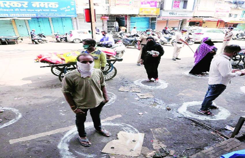 जरूरत की वस्तुएं खरीदने के लिए सुरक्षित दूरी पर खड़े लोग।