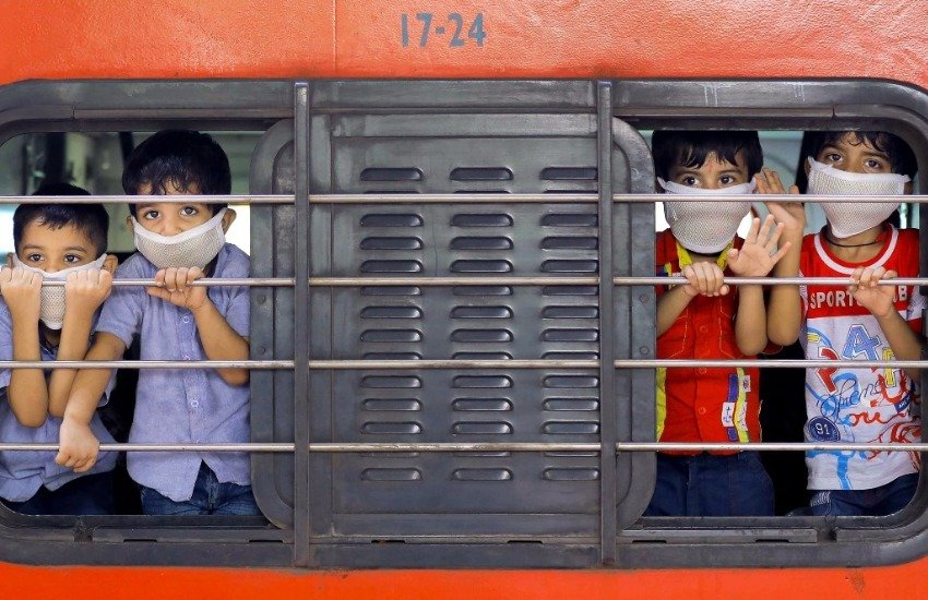 पश्चिम बंगाल के हावड़ा में राष्ट्रव्यापी लॉकडाउन के बीच राजस्थान के बीकानेर शहर के लिए ट्रेन से रवाना होते कुछ बच्चे। गाड़ी में साथ बैठे उनके परिजन। (फोटोः पीटीआई)
