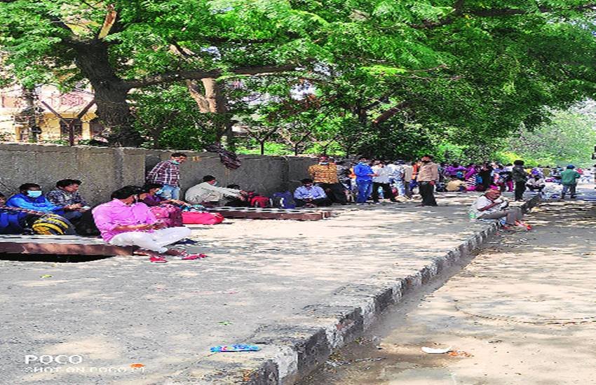 पेड़ की छाया में अपनी बारी का इंतजार करते लोग।