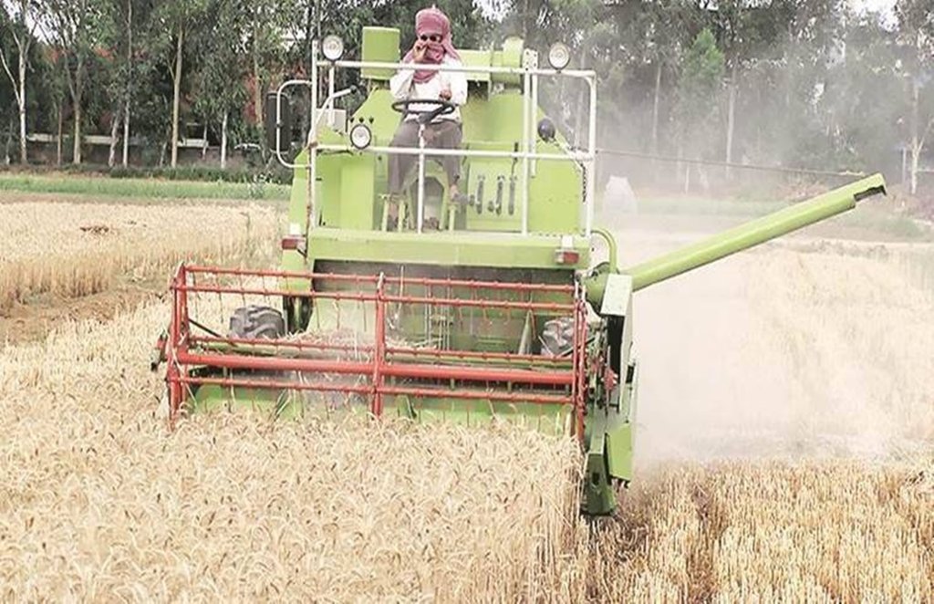 आधुनिक मशीन से गेहूं की कटाई करते किसान। फाइल फोटो।