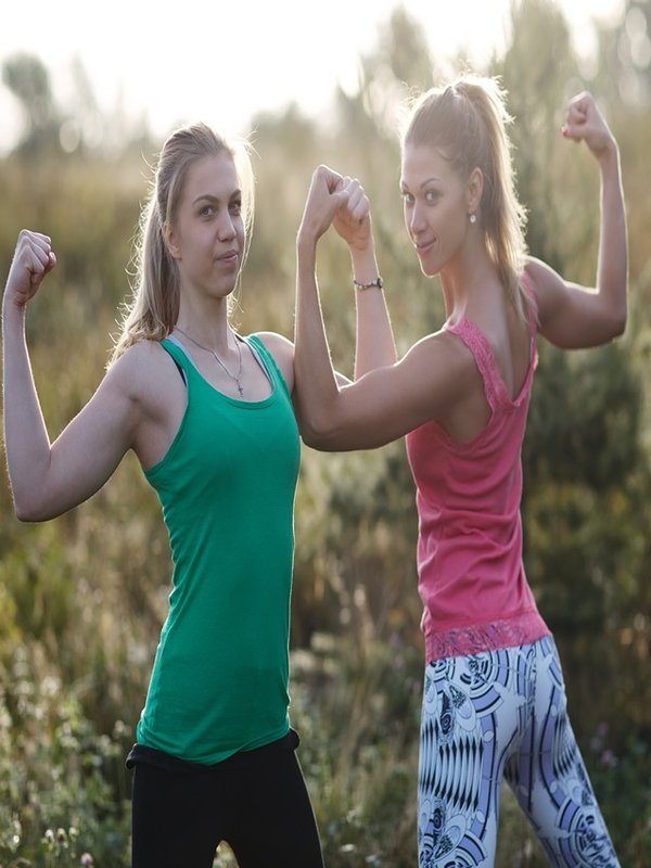 Two athletic girls flexing their arm muscles