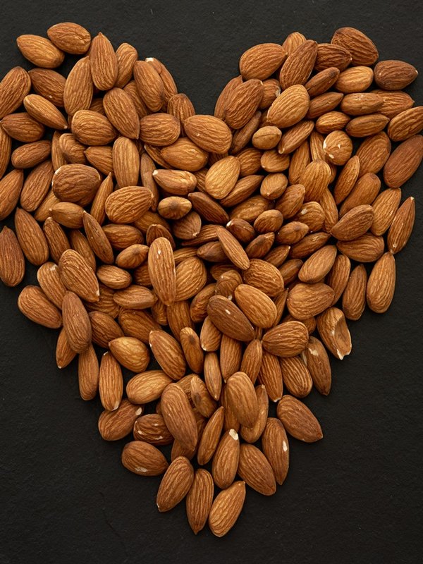 Almond nuts forming a heart-shape on black background. (selecti