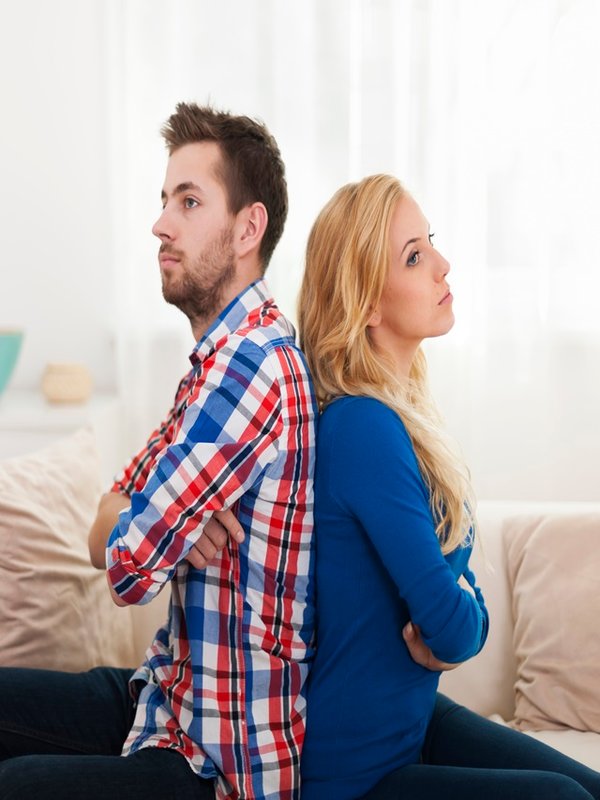 Angry young couple sitting back to back at home