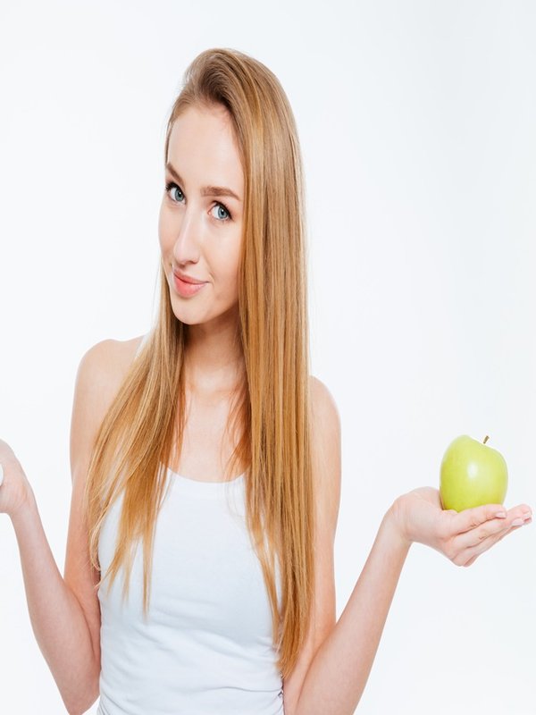 Attractive woman holding healthy and unhealthy food