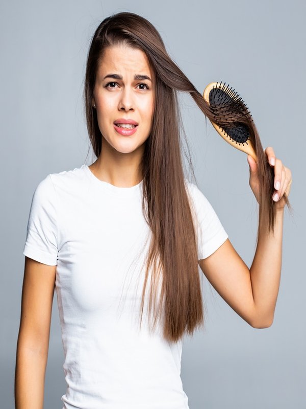Young woman problems with hair, split weak hair, tangled hair isolated on gray background