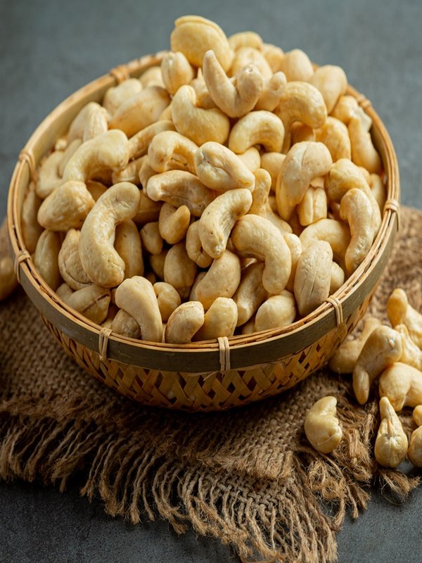 Raw cashews nuts in bowl on dark background
