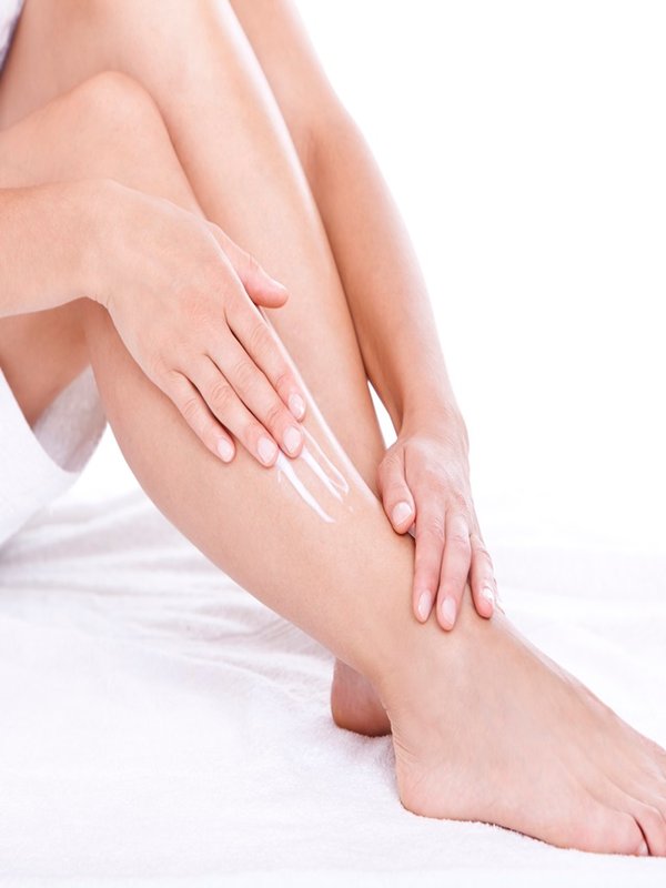 Woman applying moisturizer cream on the legs