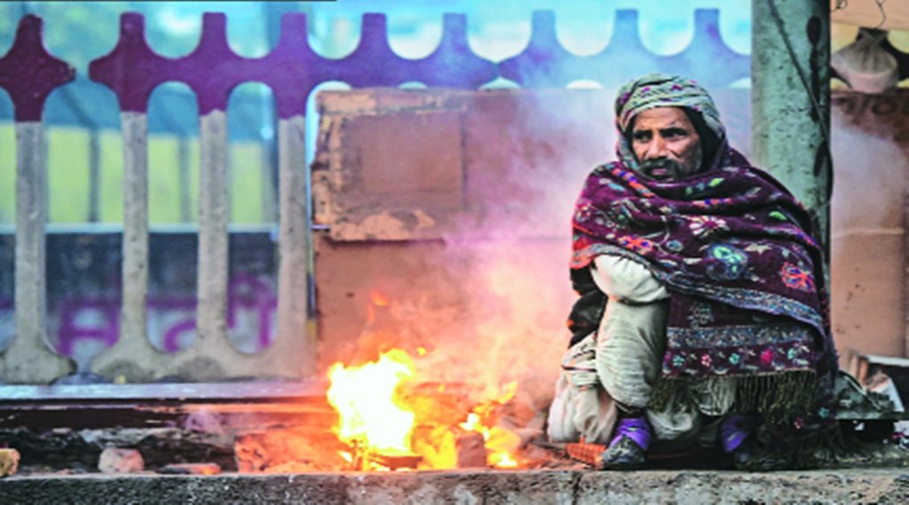 दिल्ली में आग के सामने बैठकर खुद को राहत देने की कोशिश करता ठंड से परेशान एक राहगीर। 