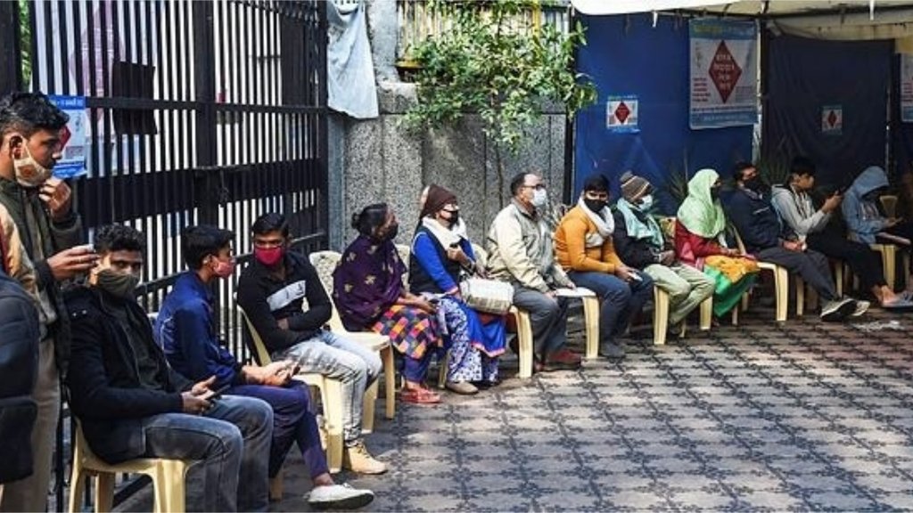 नई दिल्ली के एक टीकाकरण केंद्र के बाहर अपनी बारी का इंतजार करते लोग (फोटो: पीटीआई)