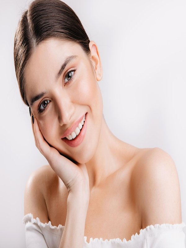Portrait of smiling girl with healthy skin. Cute dark-haired woman looking at camera on white background.
