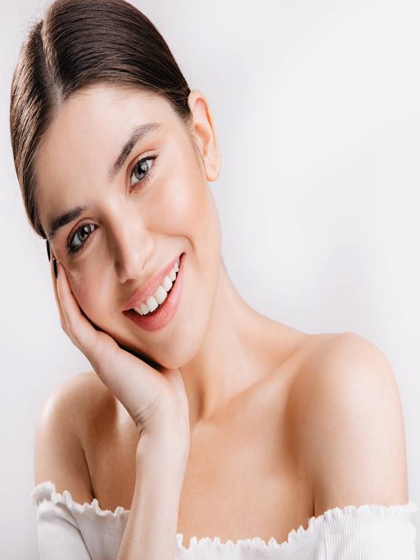 Portrait of smiling girl with healthy skin. Cute dark-haired woman looking at camera on white background.