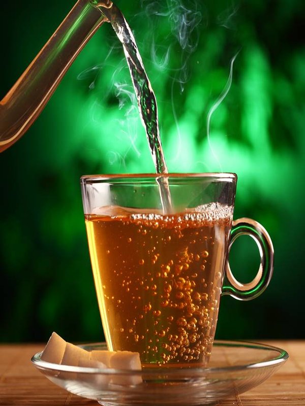 Hot green tea in glass teapot and cup