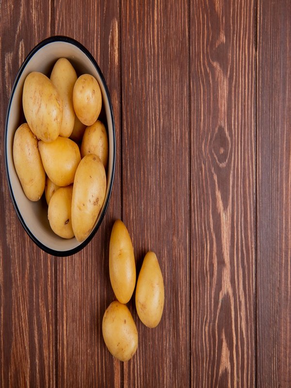 top view of new potatoes in bowl on wooden background with copy space