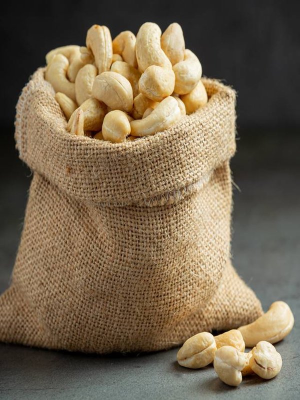 Raw cashews nuts in bag on dark background